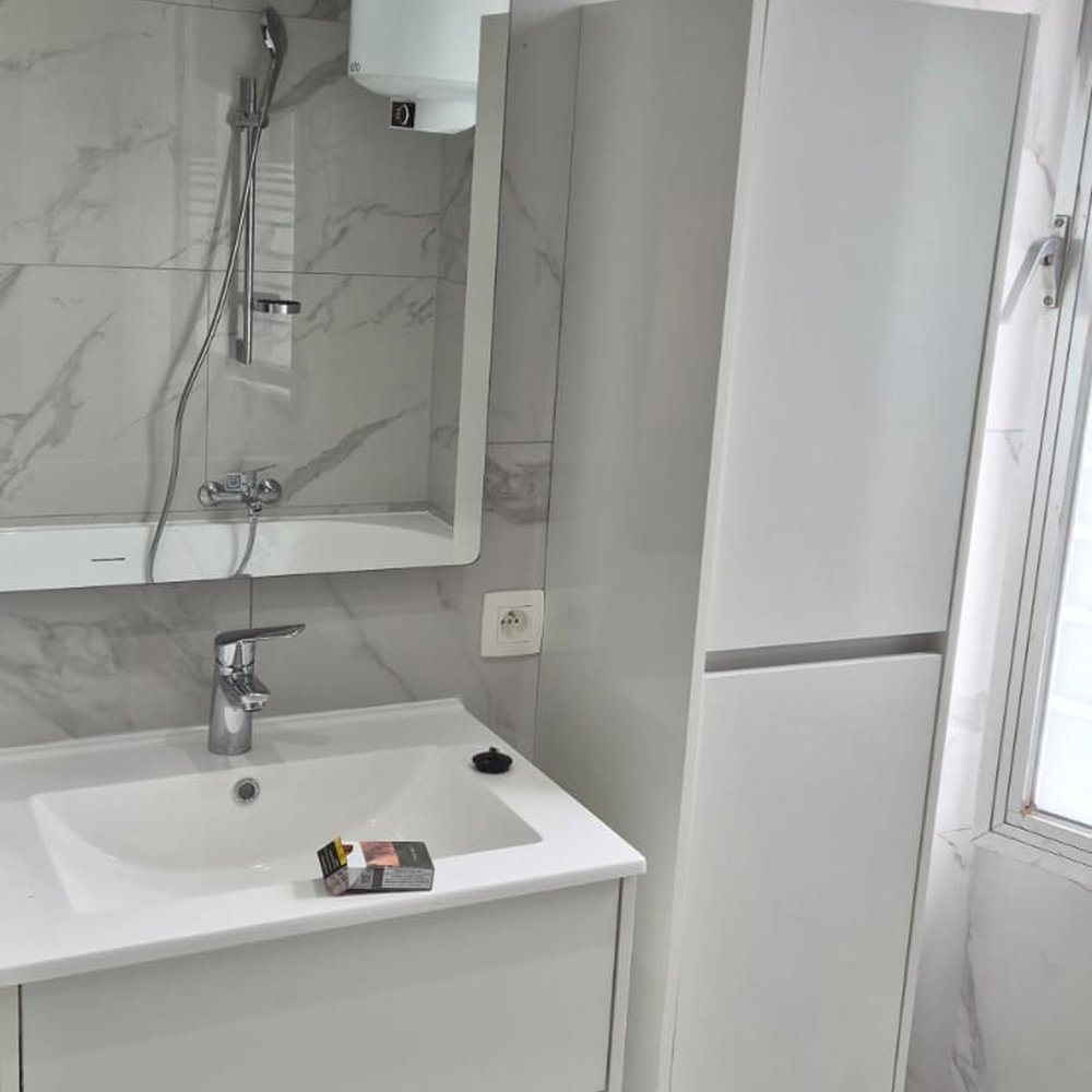 Meuble vasque et robinetterie posés dans une salle de bain en marbre