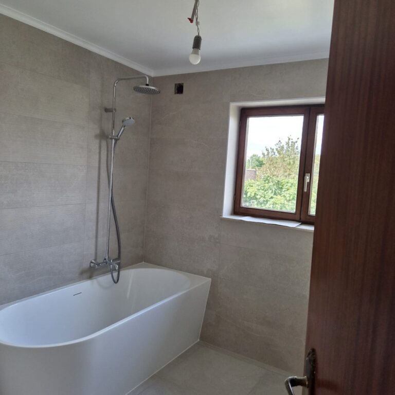 Salle de bain rénovée : baignoire îlot et carrelage grand format gris