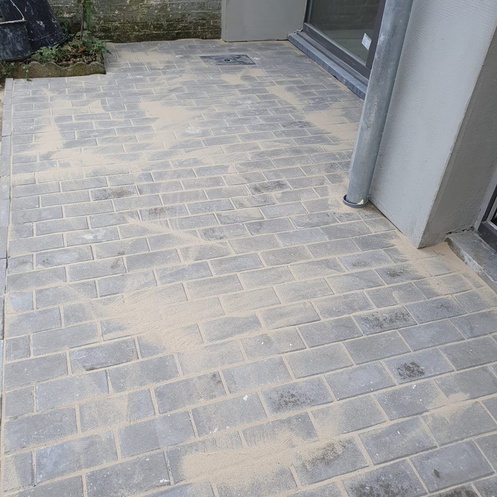 Terrasse en klinkers posée devant une baie vitrée